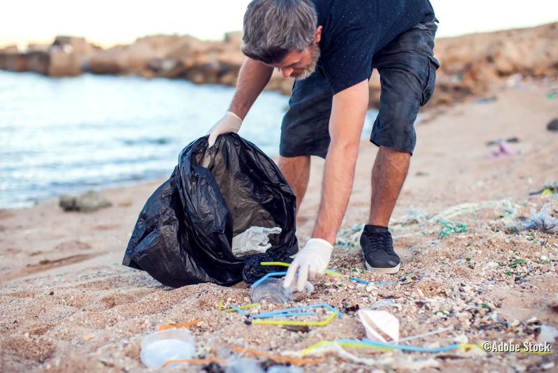 Mann macht Strand sauber