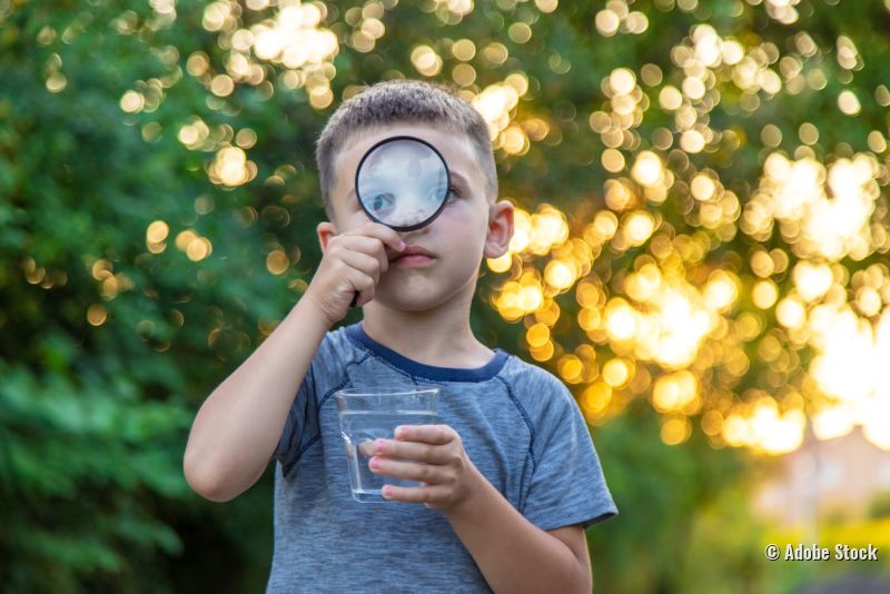 Junge untersucht Glas mit Wasser